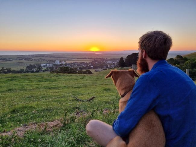 Man and dog watch sunset